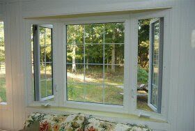 Bay window with white frames overlooking a leafy yard and trees outside.