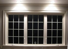 White framed window at night with grid panes and small lights above it