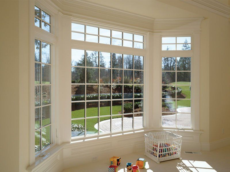 Bright bay window overlooking a green backyard, with a white basket and small toys on the floor.