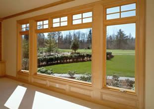 Large wooden-framed picture window overlooking a green lawn and landscaped garden
