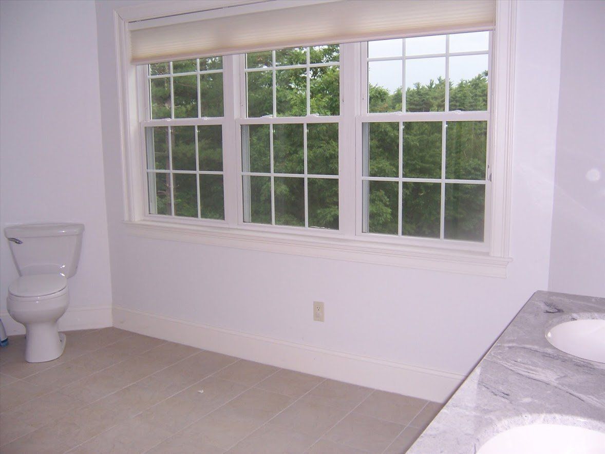 Small bathroom with a toilet, large window, and marble countertop.
