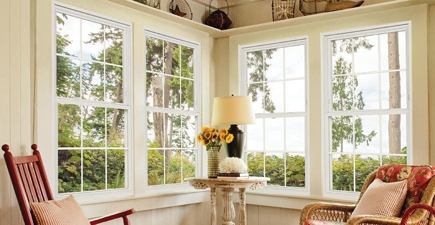 Cozy sunroom with large windows, white walls, a red chair, and a small table with flowers.