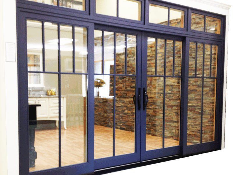 Blue-framed sliding glass doors opening to a bright interior with wood floors and a stone accent wall