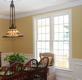 Dining room with a hanging stained-glass pendant, wooden table, and bright French doors.