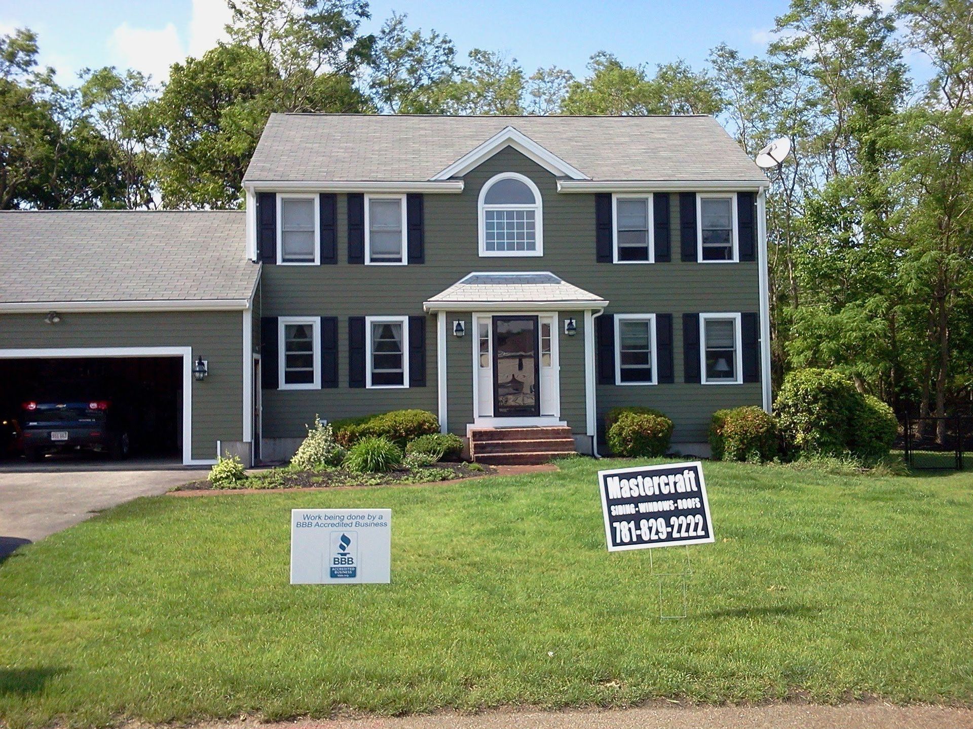 Two-story gray house with a garage and a front lawn sign for sale and open house.