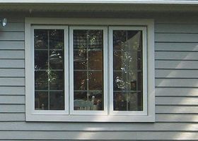 Three-pane white-framed window on gray vinyl siding