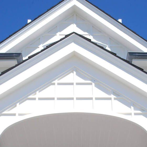 White gabled roof with decorative trim and lattice detailing against a blue sky. Siding | MasterCraft Roofing, Siding & Windows | Serving Eastern MA, NH & Selected Areas of VT
