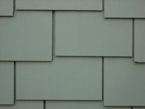 Close-up of overlapping gray roof shingles with a textured surface and staggered pattern.