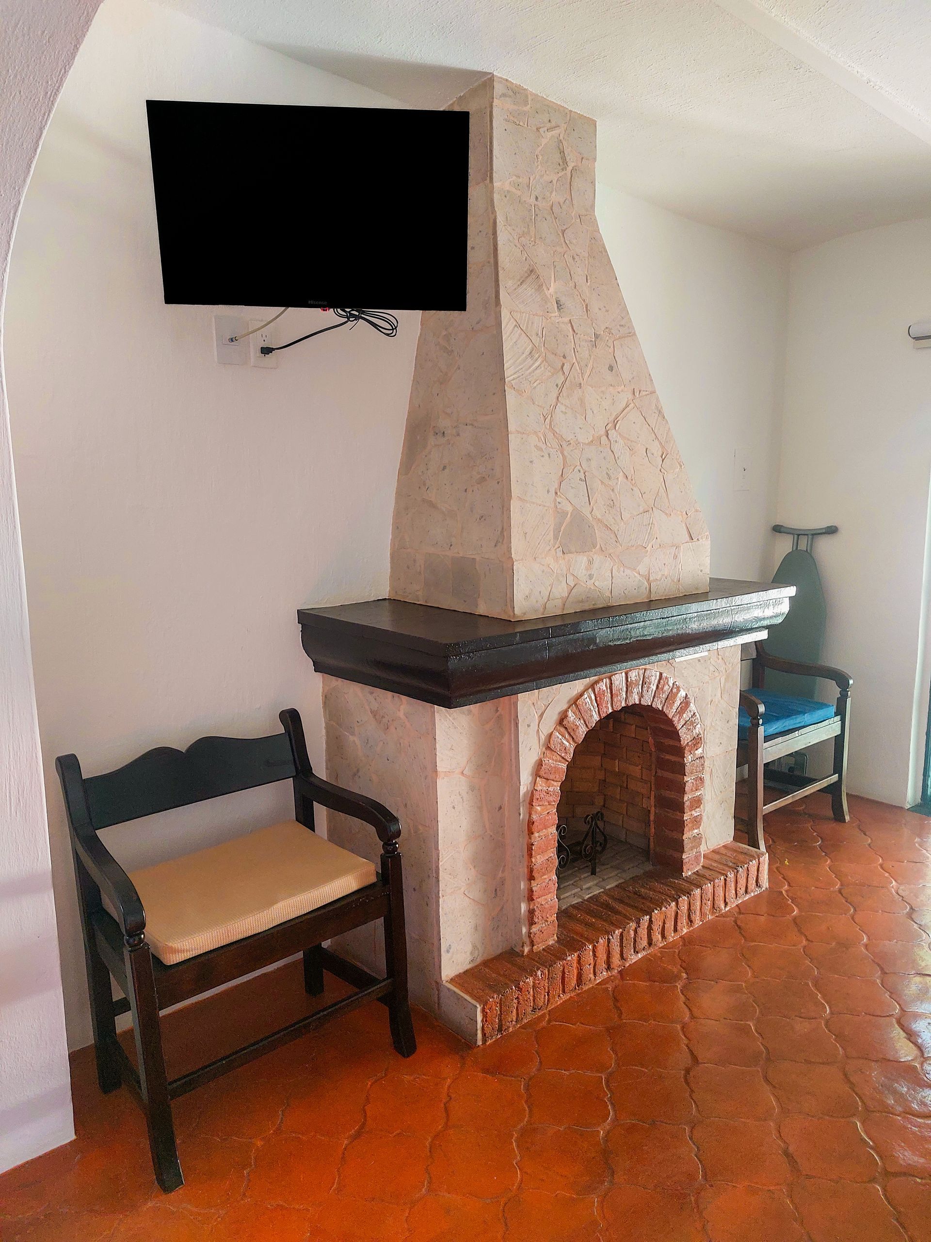 Una sala de estar con chimenea, sillas y televisión de pantalla plana.