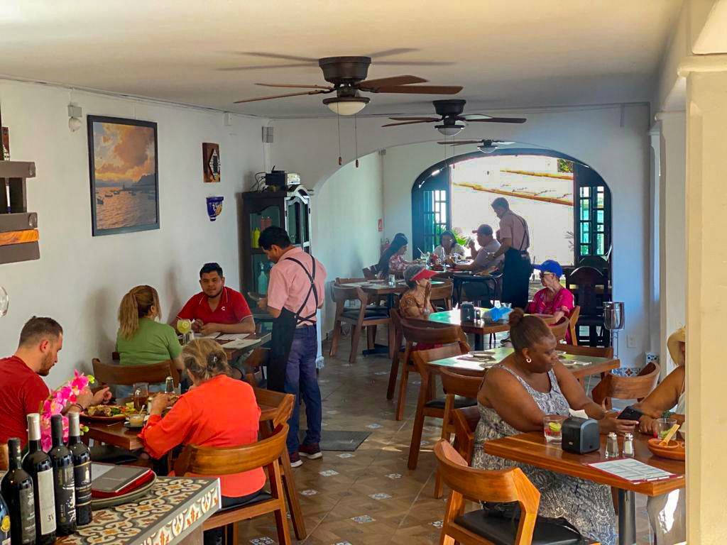Un grupo de personas están sentadas a las mesas de un restaurante.