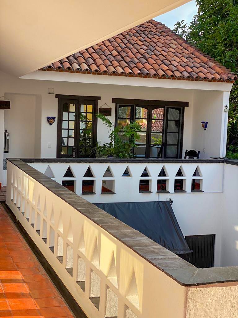 Una casa blanca con techo de tejas rojas y balcón.