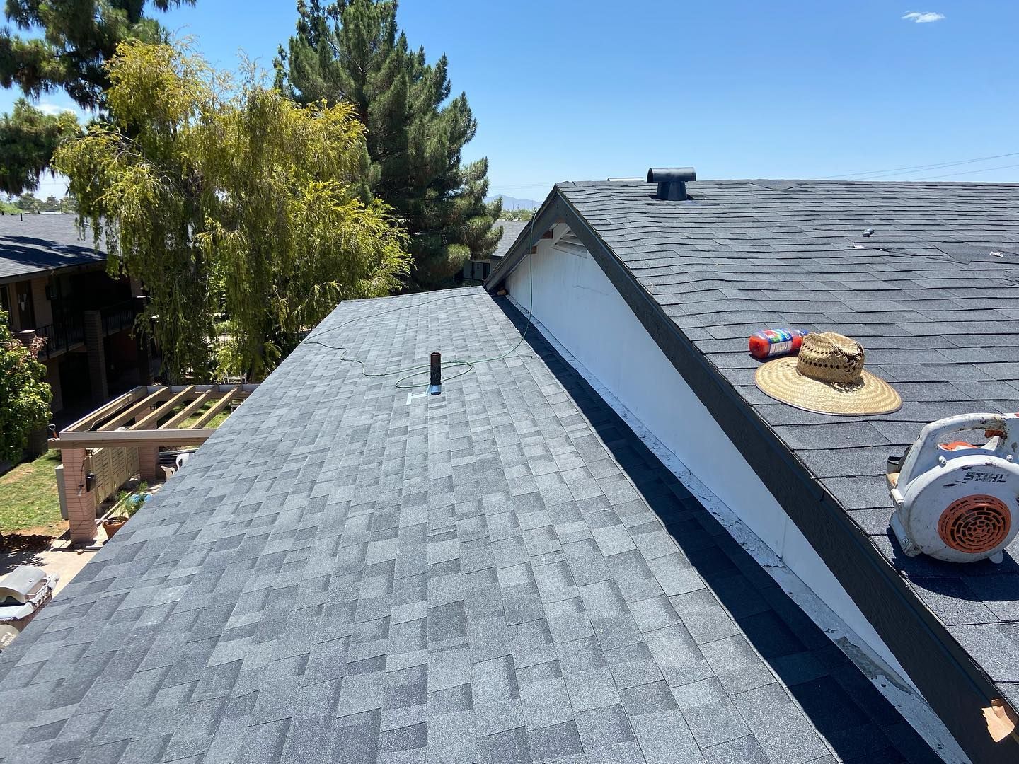 View of a roof with dark gray shingles on a sunny day.