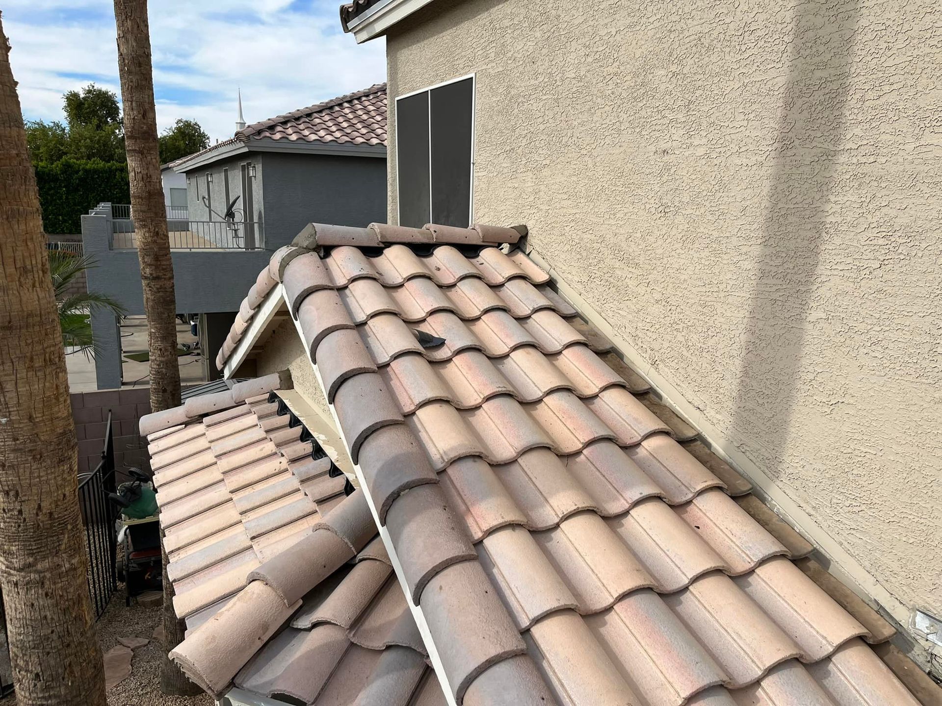 Clay tile roof on a house, angled view, beige stucco wall.