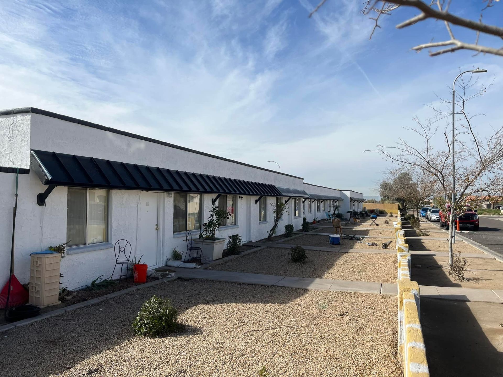 Row of white buildings with black awnings and windows on a sunny day.