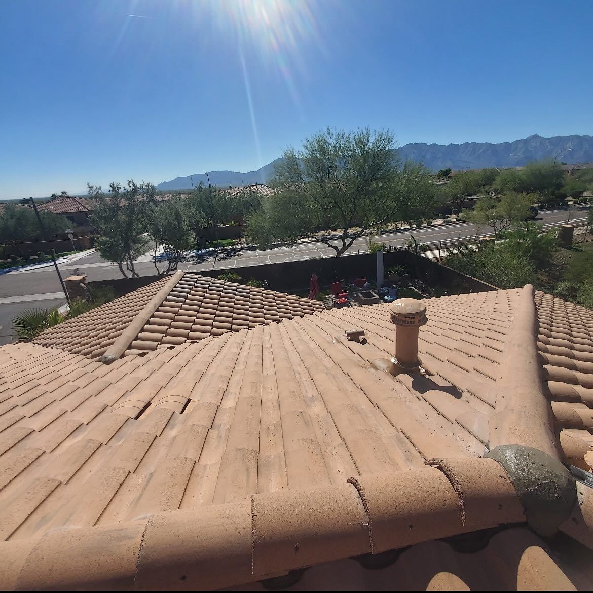 Clay tile roof on a sunny day with mountain backdrop.