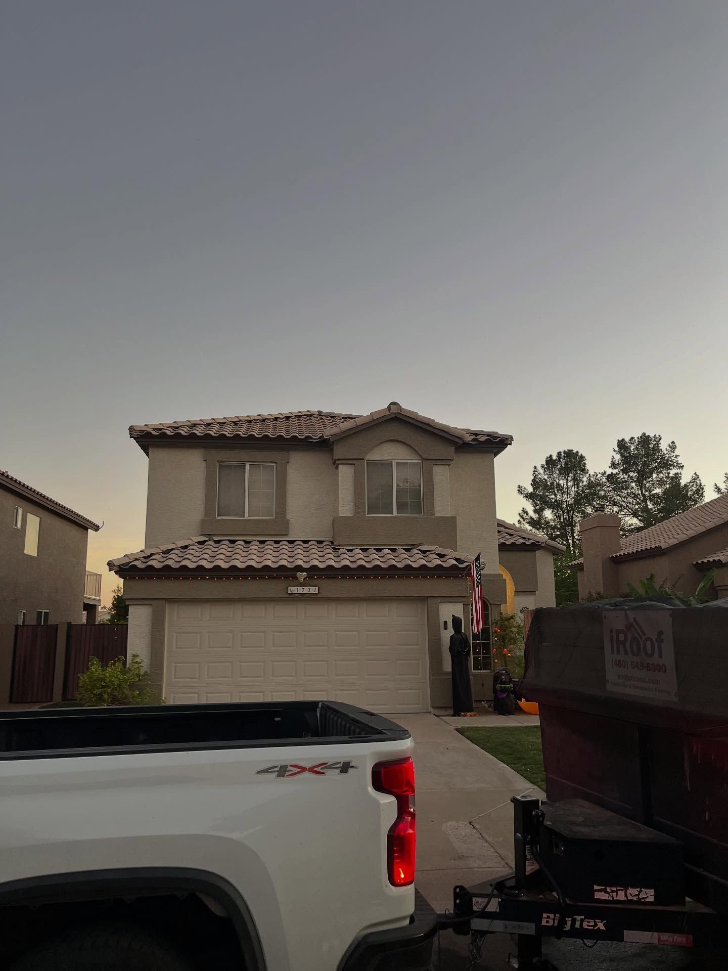 Two-story house with beige stucco, red tile roof, and a two-car garage. A white truck is in front.