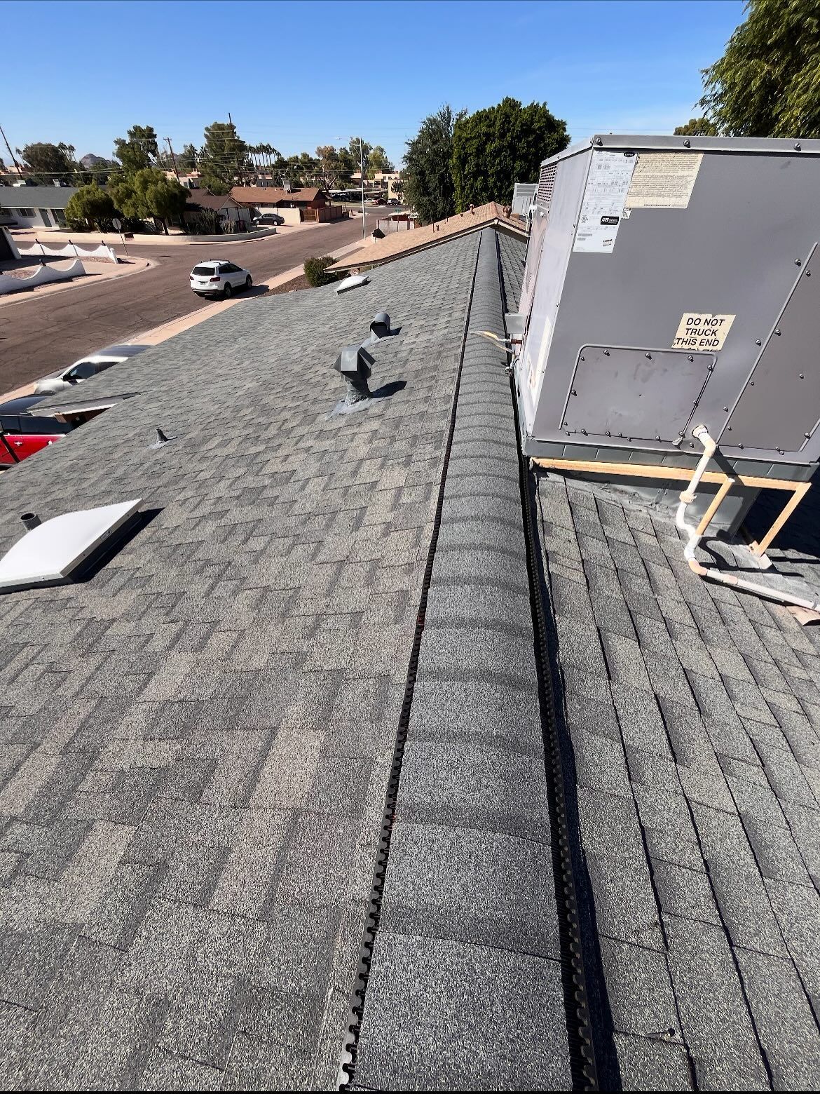 Dark gray asphalt shingle roof with an HVAC unit and neighborhood view.