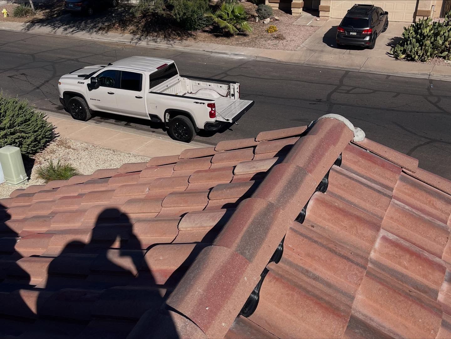 Shadow on a red tile roof, with a white pickup truck on the road in the background.