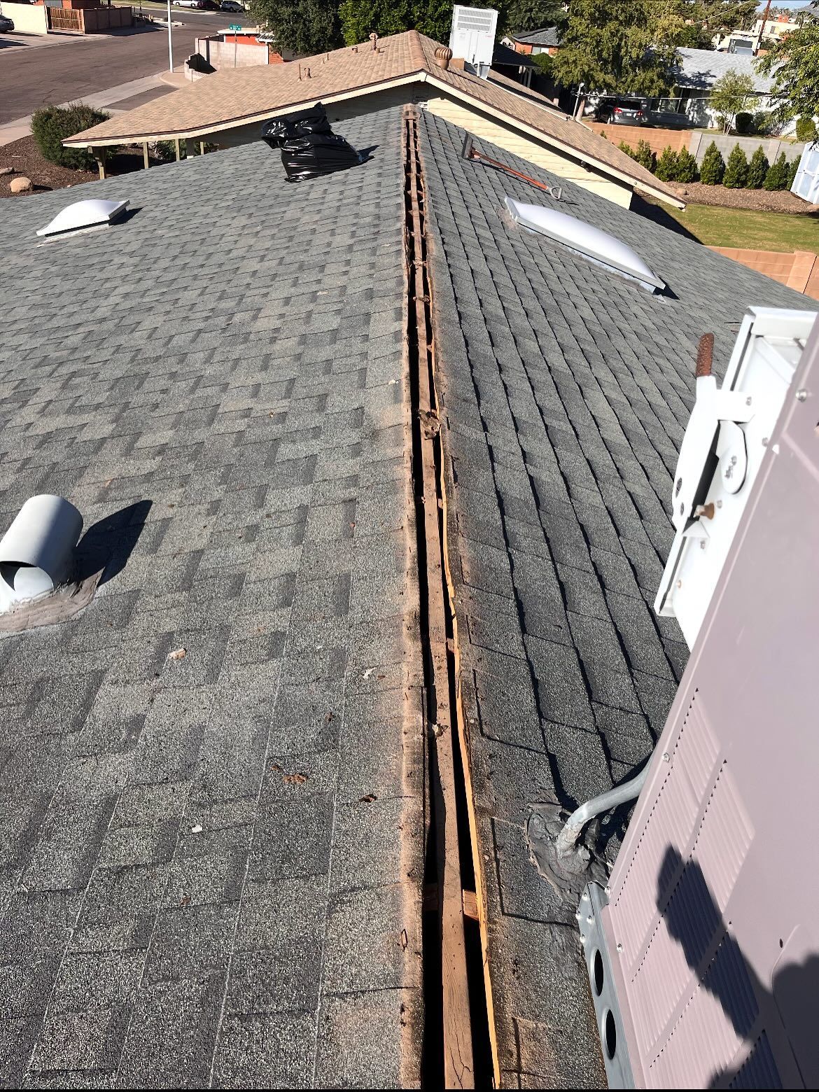Rooftop with shingles and open valley. HVAC unit and skylights visible.
