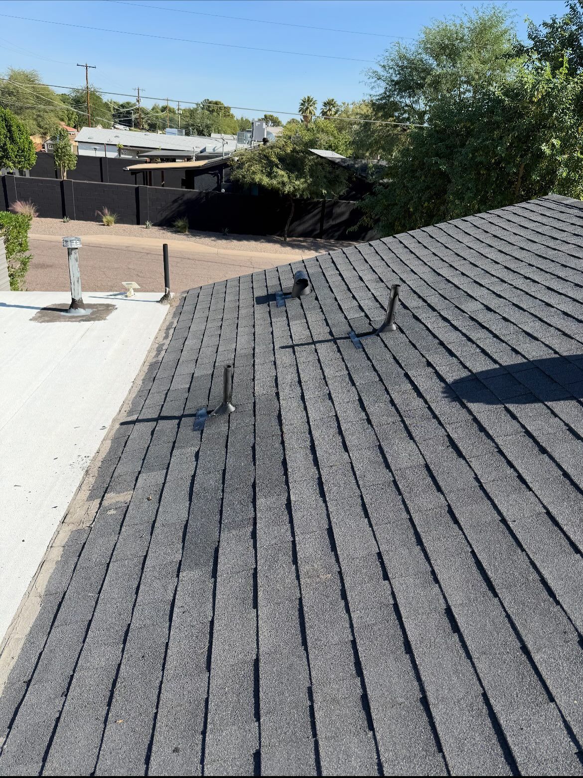 View of a dark gray shingle roof, with several vents extending upwards.