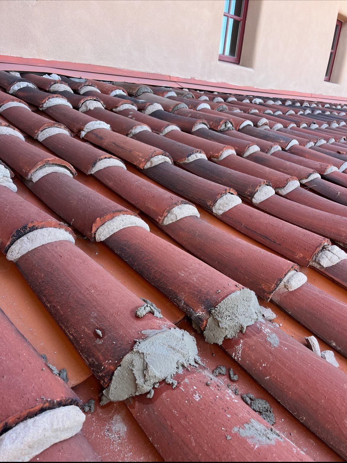 Red clay roof tiles with white mortar between them.