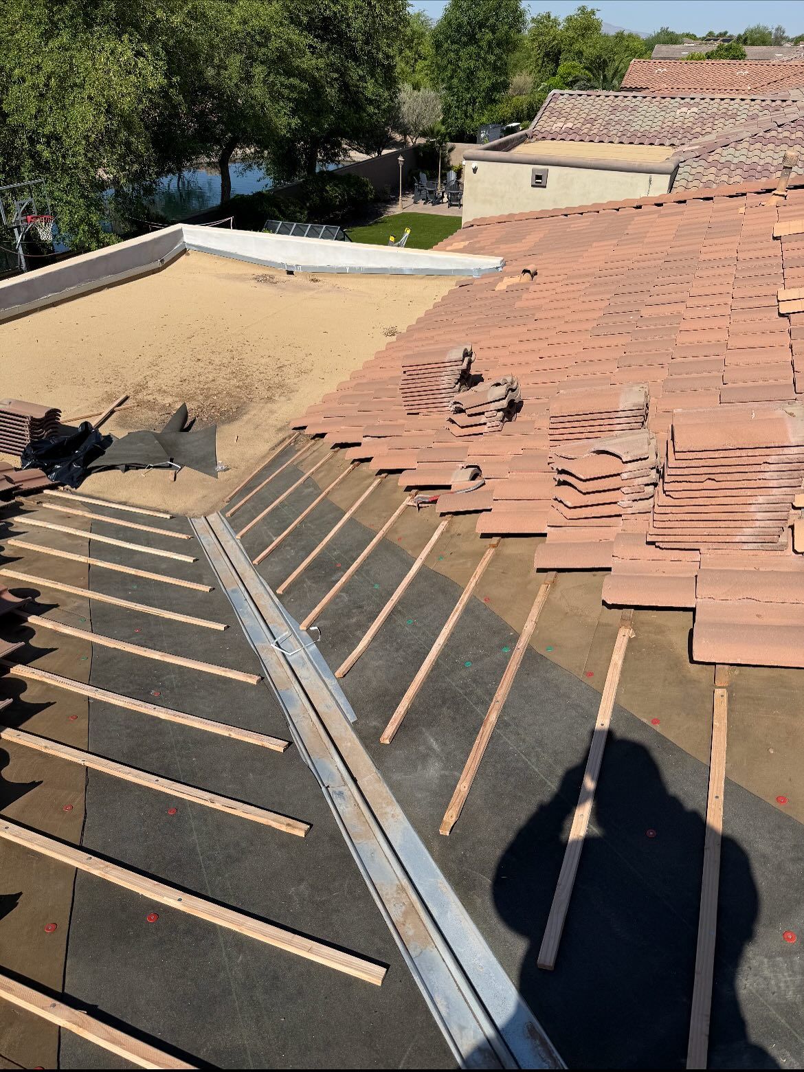Roof under construction with red clay tiles, wooden slats, and waterproof membrane.