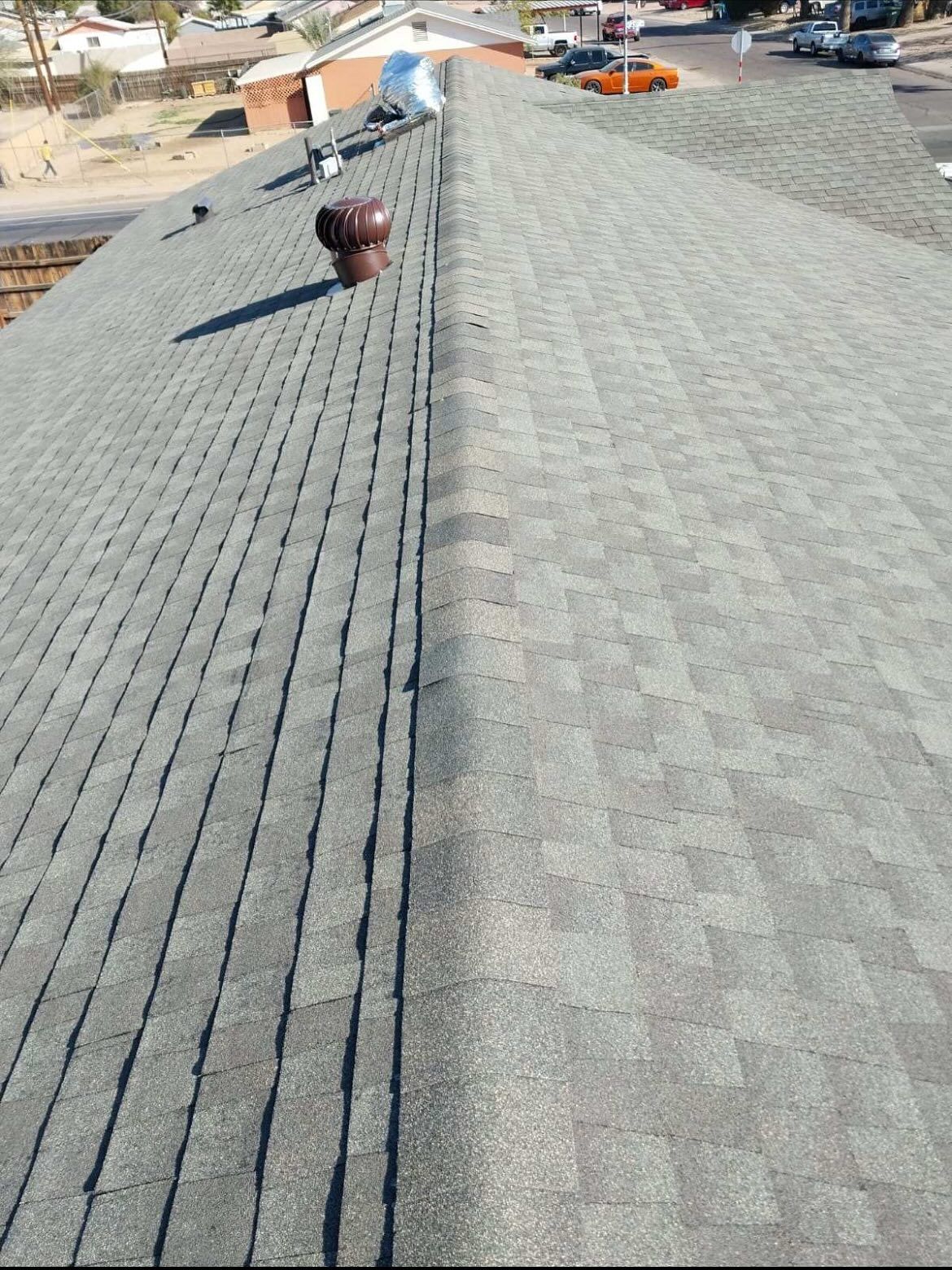 Construction workers on a rooftop with plywood, safety cones, and concrete supports under a clear blue sky.