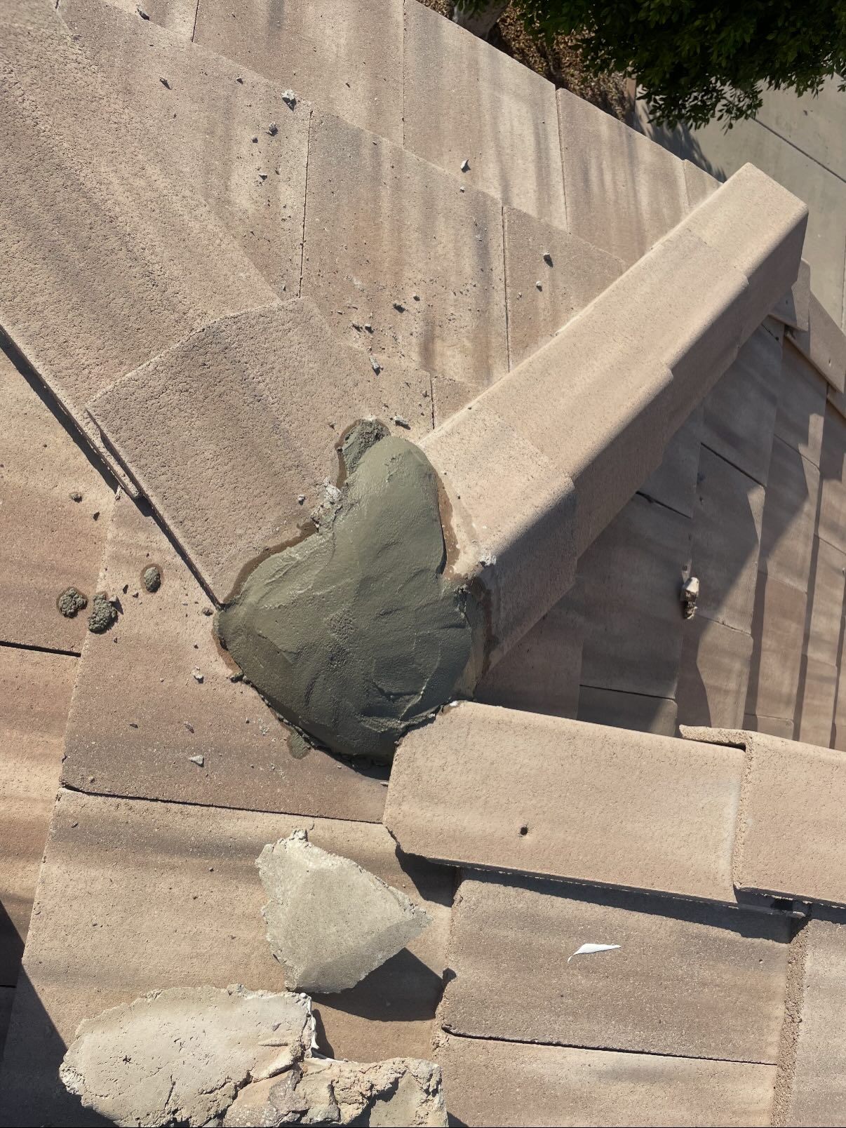 Concrete structure with repaired corner, gray-green patching material, broken pieces scattered around.