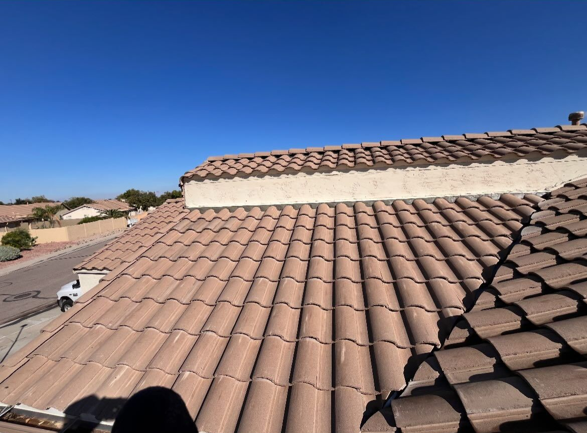 Brown tile roof with tan stucco edging against a clear blue sky.