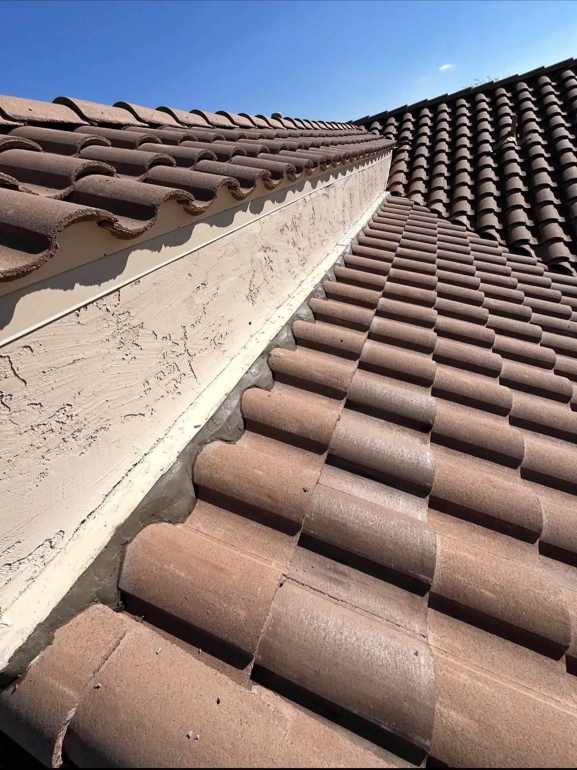 Brown tiled roof with light-colored trim against a clear blue sky.