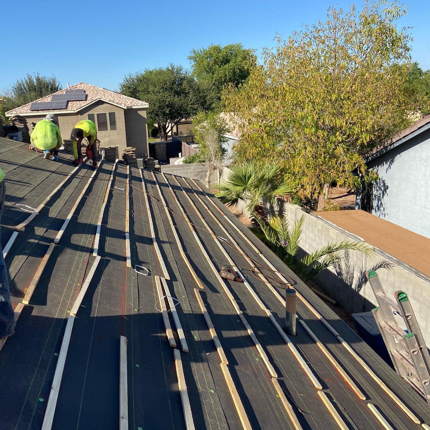 Roofers installing roofing material on a residential home under sunny conditions.