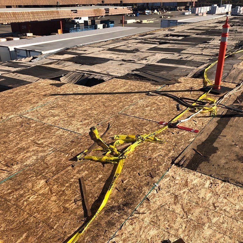 Damaged building roof with exposed wood and caution tape.