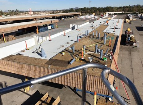 Construction site with a long, flat structure under construction, with workers and equipment present.