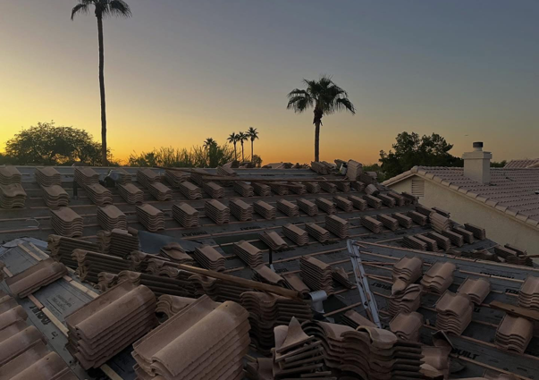 Roof tiles arranged on a roof, sunset in the background with palm trees.