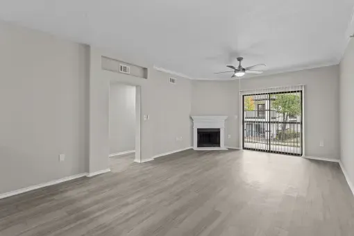 an empty living room with a fireplace and a ceiling fan