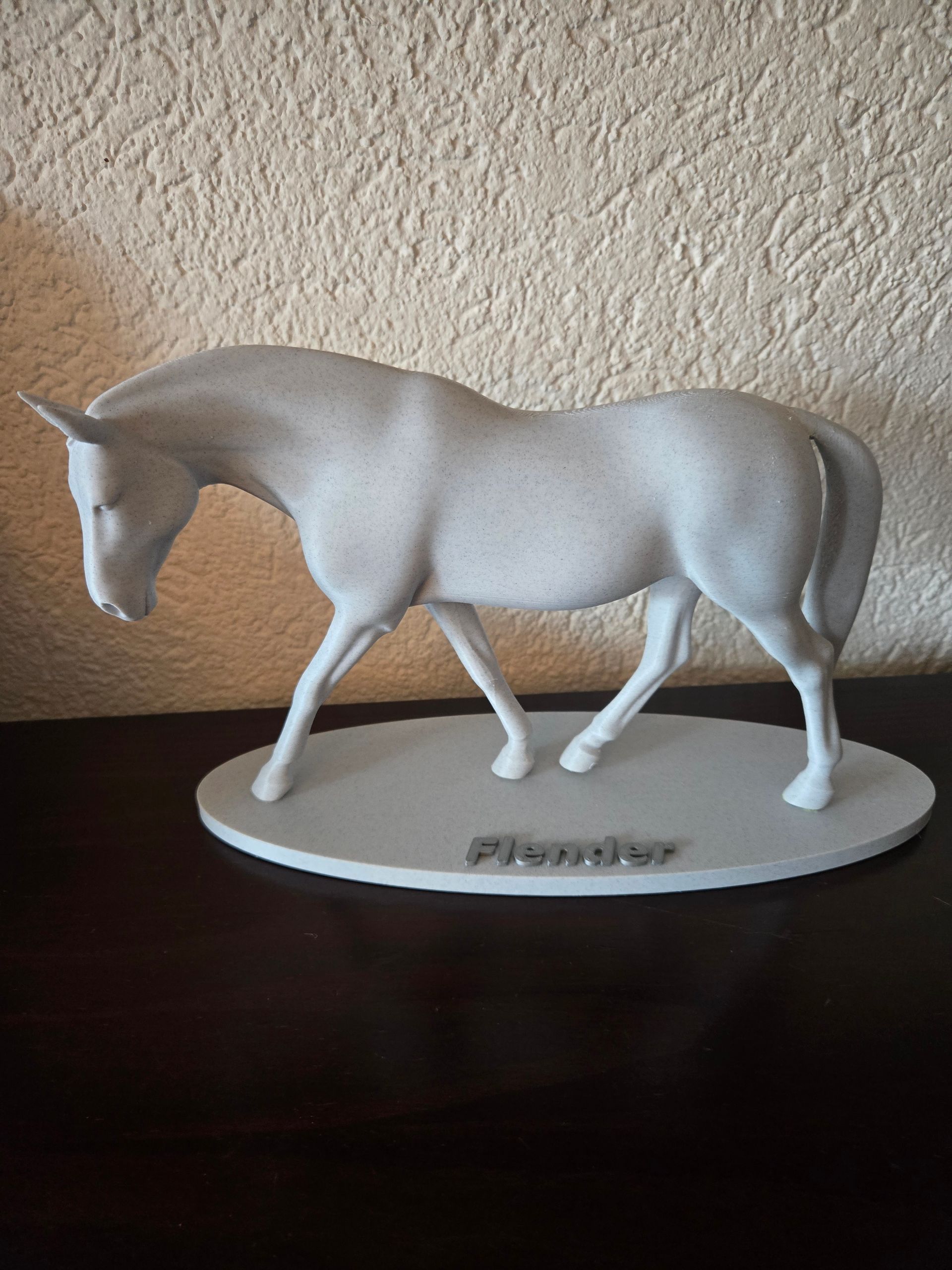 Een grijs, 3D-geprint paardje op een ovale sokkel met het woord 