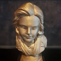 Een 3D-geprinte, metallic gouden buste van een persoon met golvend haar en gedrapeerde kleding tegen een donkere, gestructureerde achtergrond.