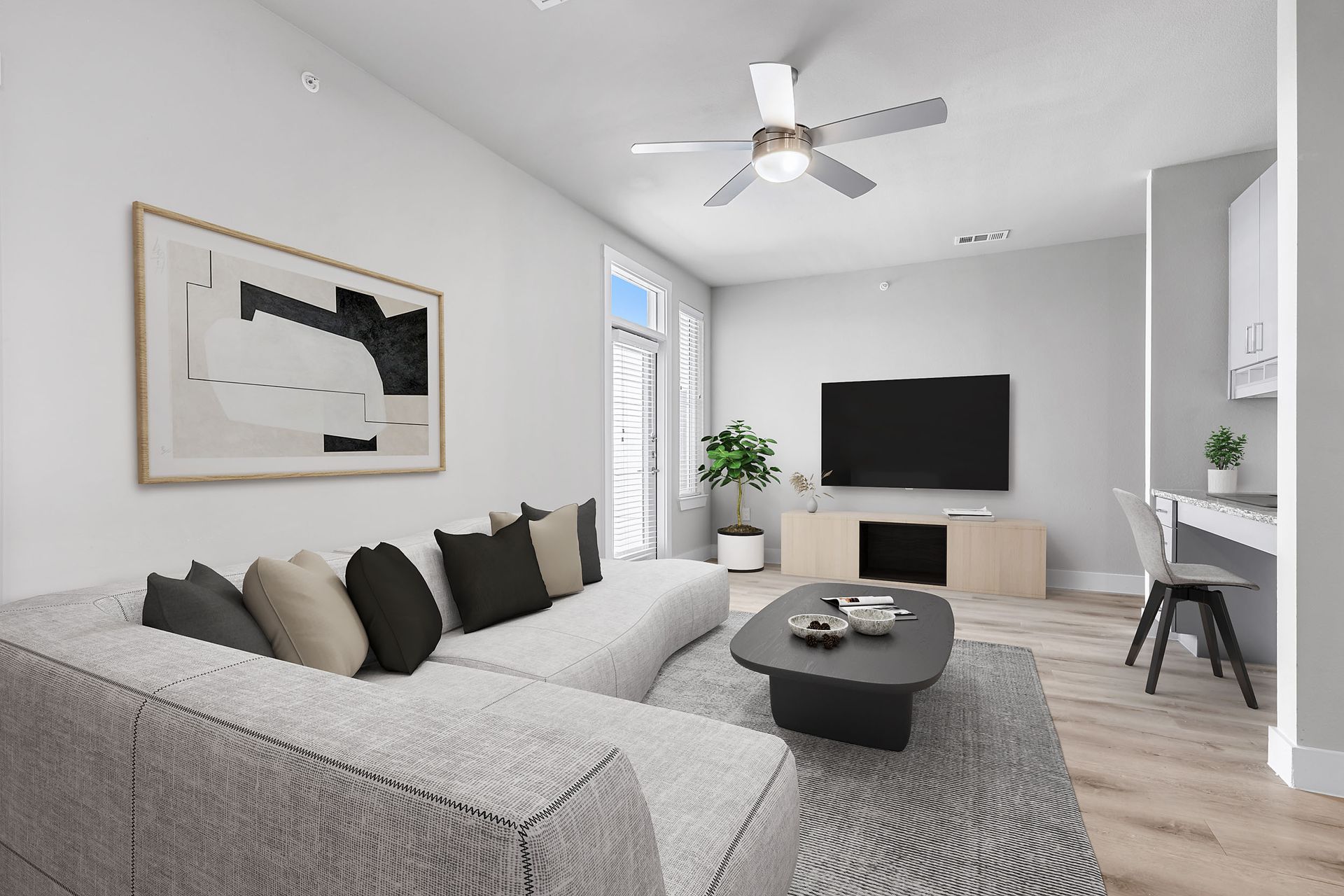 A living room with a couch, coffee table, television, and ceiling fan at The Avery, offers apartments for rent in Brushy Creek, Austin, TX.