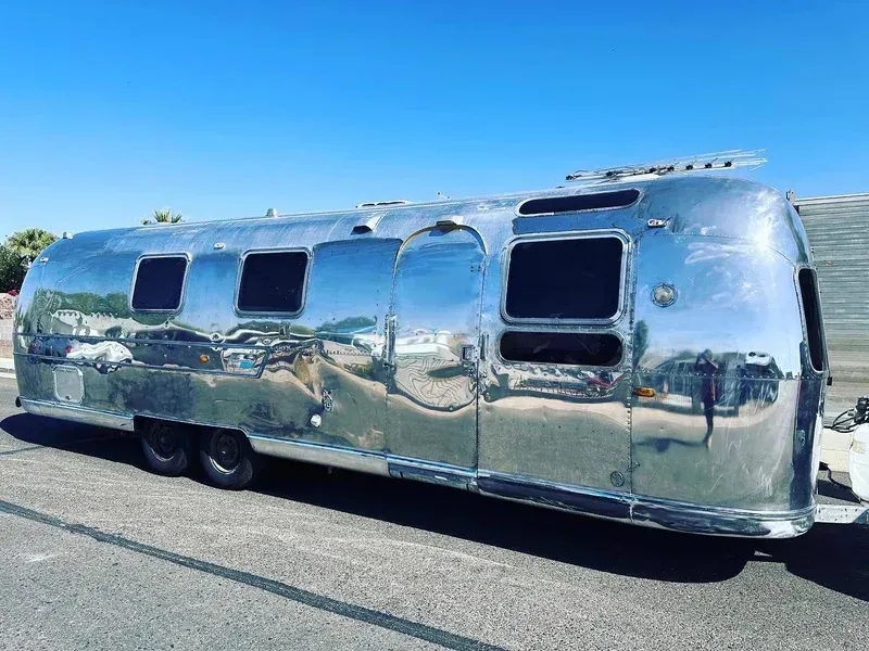 a silver airstream trailer is parked on the side of the road .