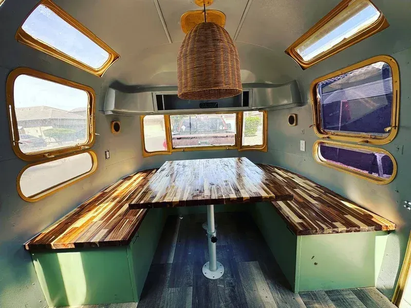the inside of an airstream trailer with a wooden table and benches .