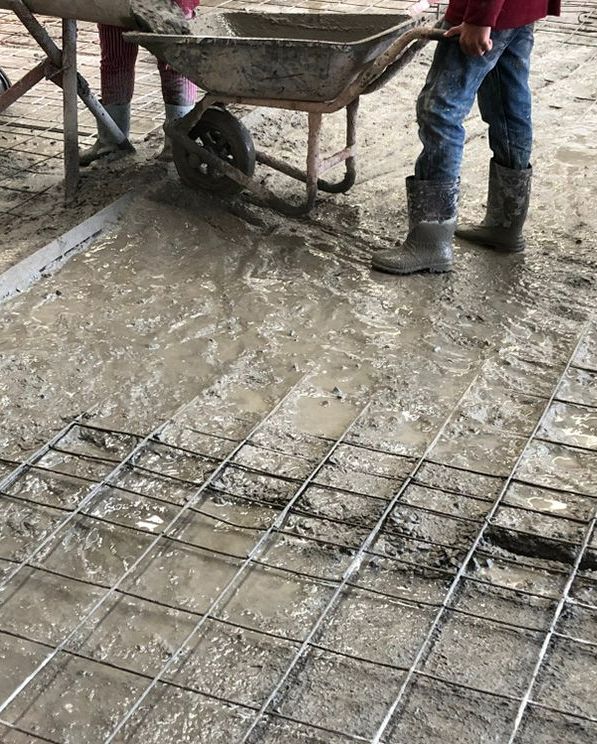 A man pouring concrete into a wheelbarrow