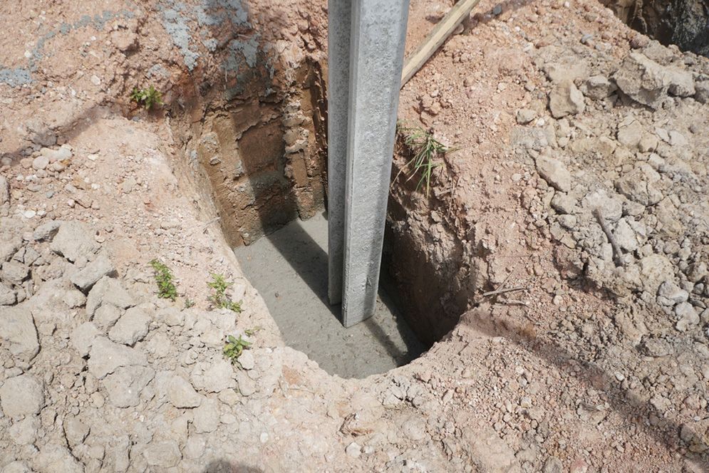 A Metal Pole is Being Installed in a Hole in the Ground — Small Batch Concrete Delivery in Tweed, NSW