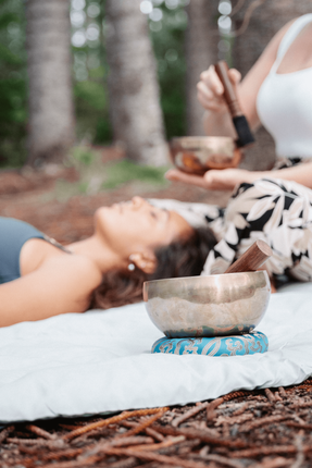 sound healer plays healing tibetan singing bowl over a young woman's head