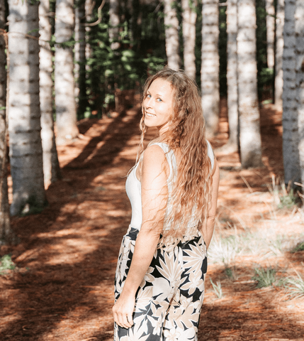 sound healer and natural healing guide jessica standing in a forest smiling at the camera