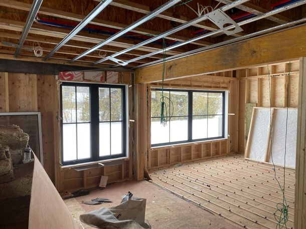Interior view of a building under construction, with wooden framework, windows, and exposed ceiling structure.