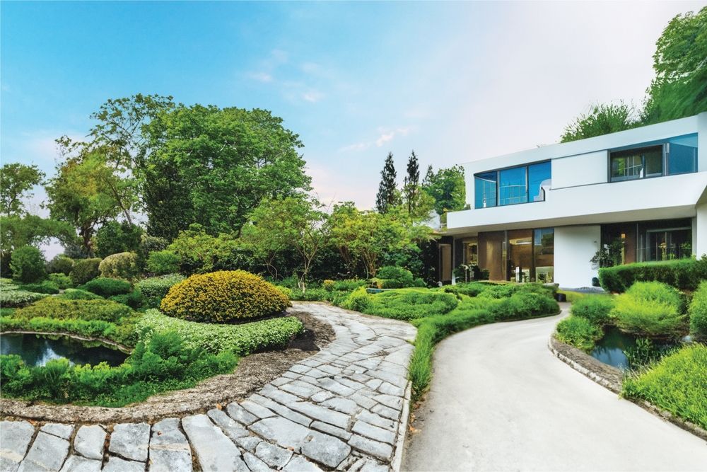 A large white house is surrounded by a lush green garden.