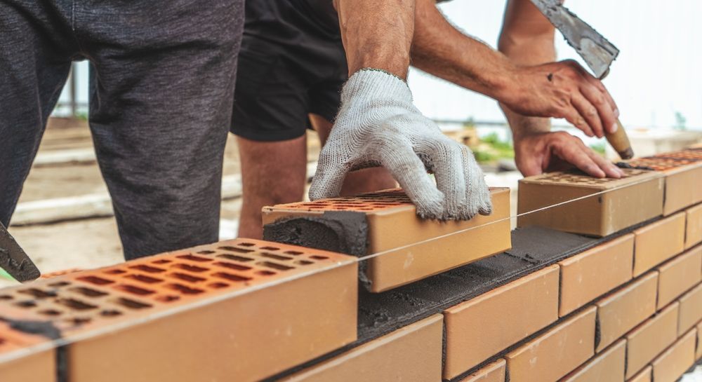 A couple of men are building a brick wall.