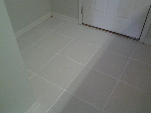 A white tiled floor in a room next to a door.