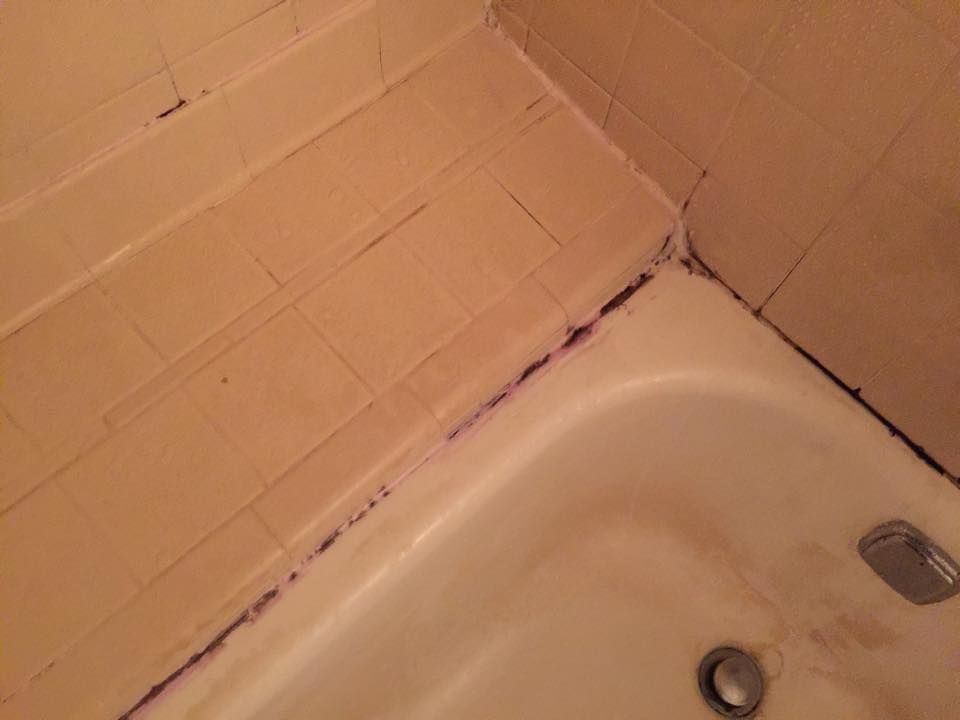 A bathtub in a bathroom with a tiled floor and a drain.