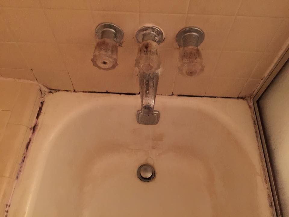 A bathtub with a faucet and a drain in a bathroom.